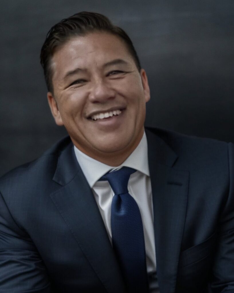 Duane Samson, smiling, in a navy suit and tie
